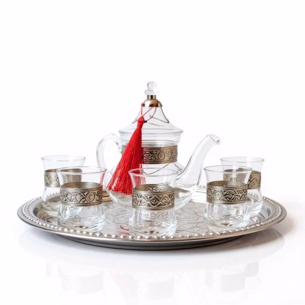 Elegant glass tea set with silver-engraved teapot and matching glasses on decorative tray