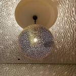 Engraved brass sphere pendant casting detailed shadows