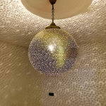 Illuminated brass globe pendant creating celestial light patterns