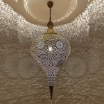 Illuminated brass light shade casting intricate shadow patterns