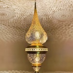 Illuminated brass pendant lamp shade creating intricate light patterns