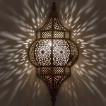 Illuminated brass wall sconce showing intricate shadow patterns