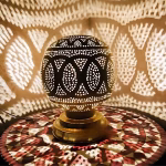 Illuminated round bedside lamp creating leaf shadow patterns