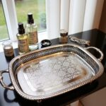Silver-plated brass oval serving tray organizing beauty products and perfumes on a white vanity