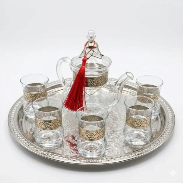 Studio product photography of a silver engraved glass tea set featuring a glass teapot and six glasses with intricate silver bands on a matching engraved tray.