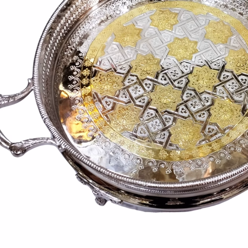 Close-up detail of silver big round tray with gold accented floral patterns and geometric designs