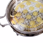 Close-up detail of silver big round tray with gold accented floral patterns and geometric designs