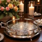 Large silver tray on dark wood table beside roses and lit pillar candles