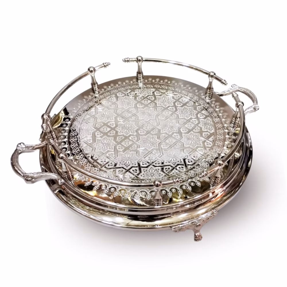 Hand-engraved silver large round tray with detailed geometric pattern and decorative feet viewed from an angle