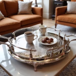 Large silver round tray with decorative handles serving coffee and cookies in cozy living room setting