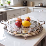 Silver large round tray with decorative handles and feet holding fresh fruit in modern kitchen setting