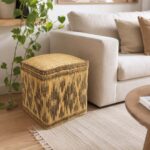 Natural straw floor pouf placed beside a light beige couch on a neutral woven area rug in a living room.