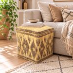 Square woven straw floor pouf functioning as a side table with decorative books on top next to a sofa.