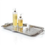 Engraved silver-plated serving tray with ornate handles displaying soap dispensers and cosmetics in elegant setting