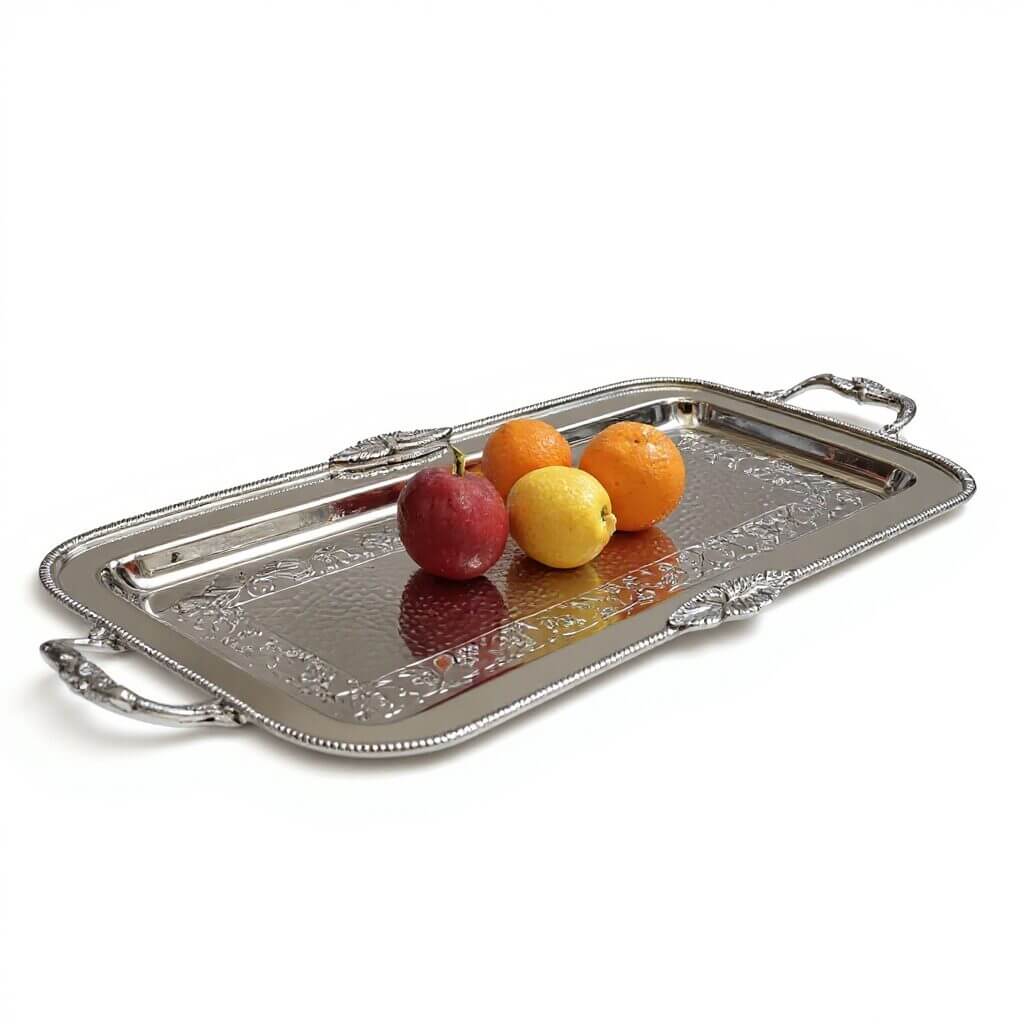 Elegant silver plated rectangular decorative tray with hammered center and ornate border design Hand-engraved silver serving tray with ornate handles displaying fresh fruit on reflective polished surface