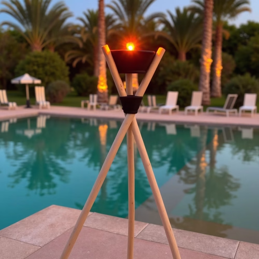 Poolside wooden tripod torch holder creating romantic ambiance with palm trees in background