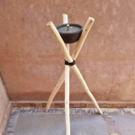 Traditional Moroccan wooden tripod torch holder with ceramic bowl on desert sand patio