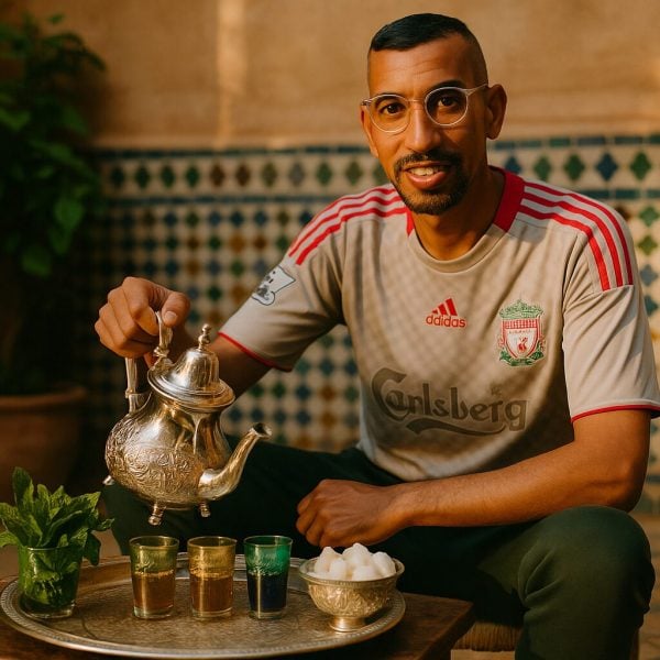 Kamal presenting a silver teapot on a Moroccan tea tray with colorful tea glasses and fresh mint in a riad courtyard.