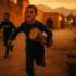 Amazigh boy carrying ta'arija drum during Achoura in Marrakech medina, with traditional fakia basket