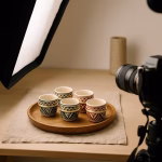 Behind-the-scenes shot of a DSLR camera and softbox capturing six Moroccan espresso cups arranged on a round wooden tray.