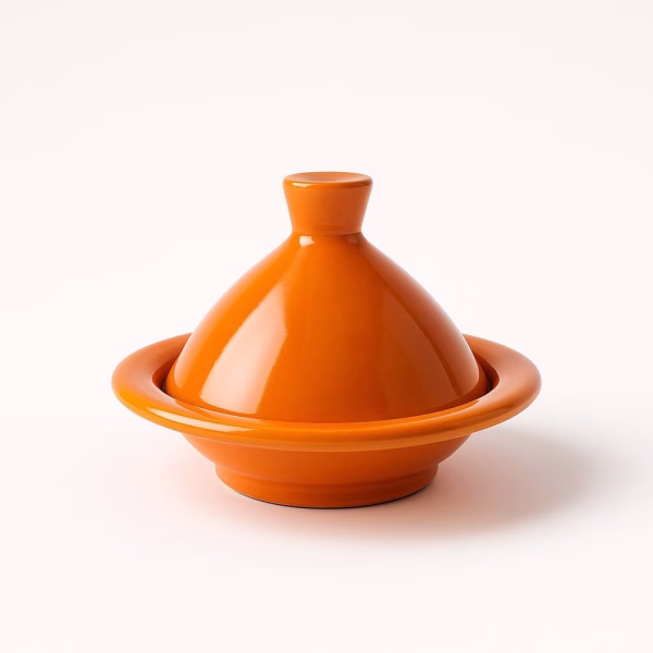 Bright orange ceramic mini tagine with high-gloss glaze, isolated on a white background.