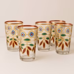 Five Moroccan floral tea glasses clustered together, highlighting red, green, and blue enamel leaves.
