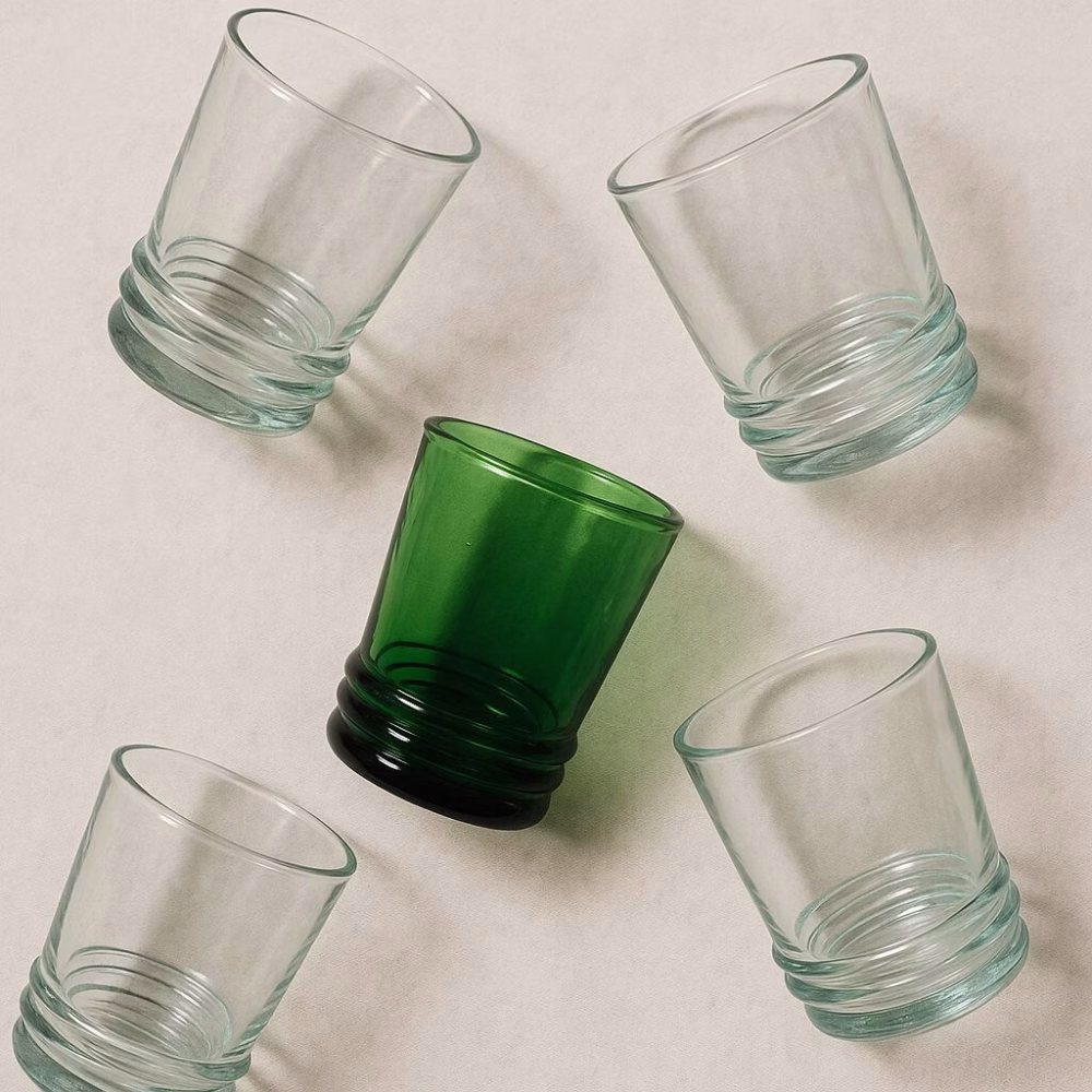 Five recycled Moroccan drinking glasses in playful flat-lay pattern.