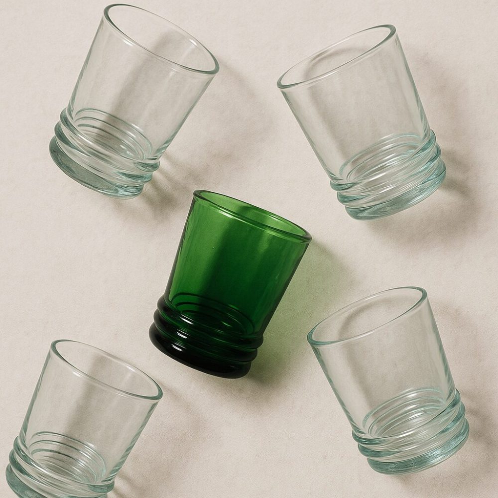 Five recycled Moroccan drinking glasses in playful flat-lay pattern.