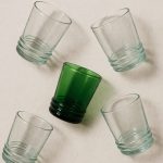Five recycled Moroccan drinking glasses in playful flat-lay pattern.
