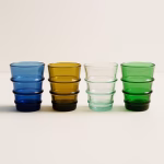 Four sapphire Moroccan glass tumblers (blue, amber, clear, green) showcased on a white backdrop.
