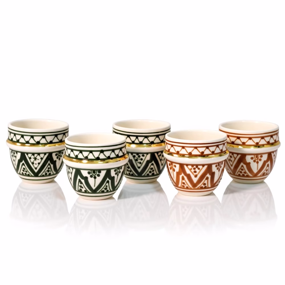 Mixed green and amber espresso cups reflecting on glossy surface.