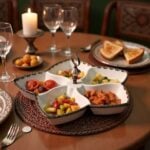 Ceramic divided plate with silver handle serving mixed vegetables and appetizers at dinner table
