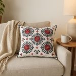 Rectangle shot of Moroccan embroidered pillowcase resting against knit blanket on armchair.