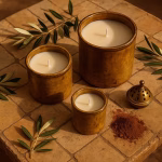 Set of three brown pottery candles (S, M, L) on sun-baked zellige tiles with olive branches and brass censer.