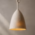 Side view of the suspended boiled-wool lamp with sculptural woolen cord against a neutral plastered wall.