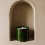 Single green pottery candle displayed in a curved wall niche against smooth tadelakt plaster.