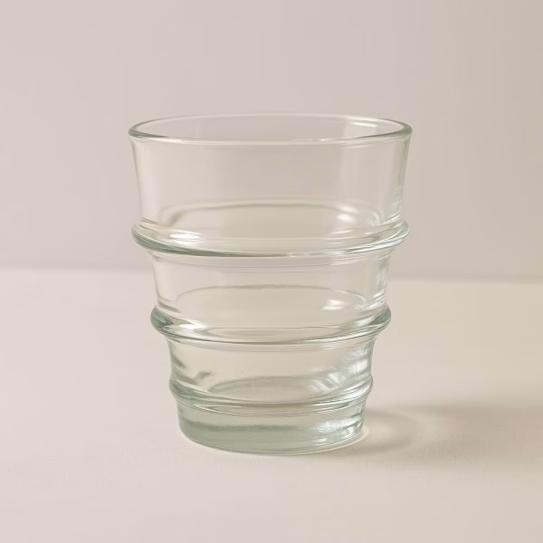 Studio close-up of a clear recycled glass tumbler with ribbed rings.