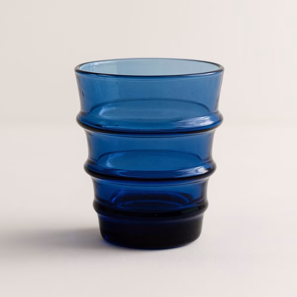 Studio close-up of a cobalt-blue recycled glass tumbler with ribbed rings.