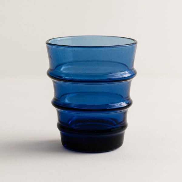 Studio close-up of a cobalt-blue recycled glass tumbler with ribbed rings.