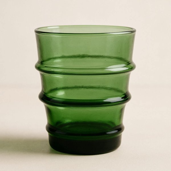 Studio close-up of a green recycled glass tumbler with ribbed rings.