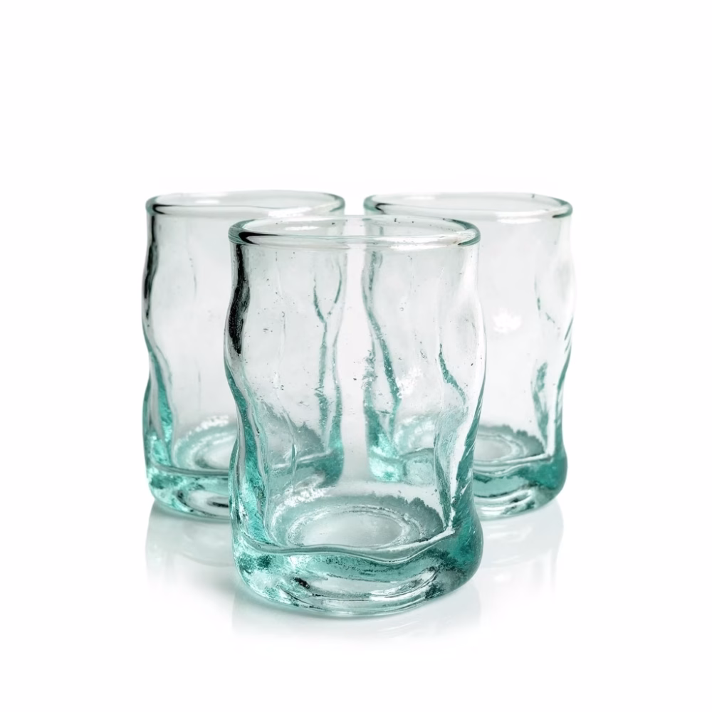 Studio shot of three wavy Moroccan recycled glass cups against a white background.
