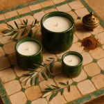 Trio of green pottery candles (S, M, L) on vintage green-trimmed tiles with ground cinnamon and olives.
