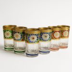 Studio shot of six handcrafted Moroccan tea glasses set pieces against a clean white backdrop.