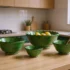 Three green Moroccan Tamegroute pottery bowls styled on small kitchen counter with fruits and utensils