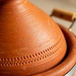 Detail of terracotta tagine pot showing carved geometric patterns and natural clay texture