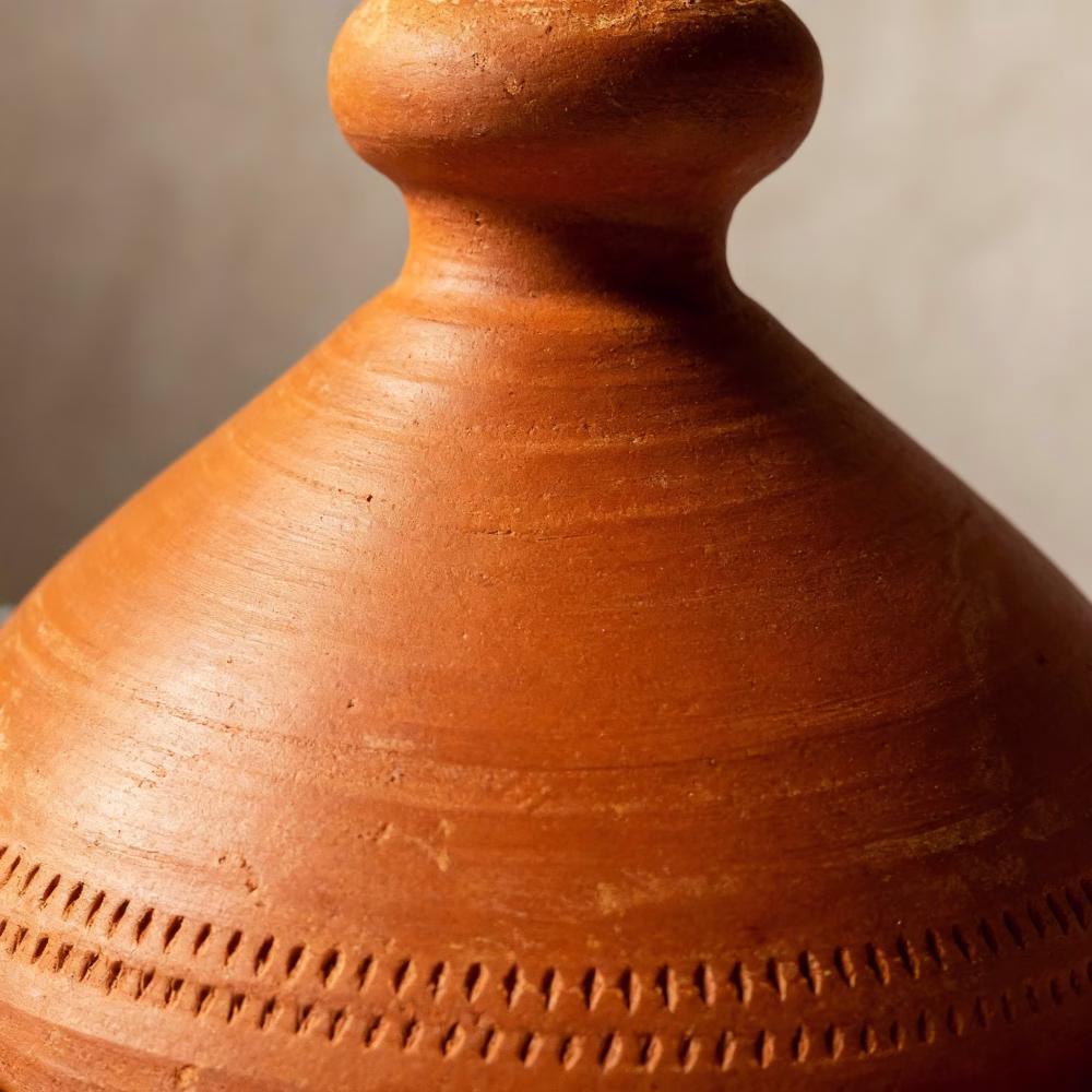 Close-up of handmade Moroccan terracotta tagine lid showing traditional carved geometric patterns
