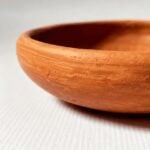 Close-up of handcrafted terracotta ceramic plate rim showing natural wheel-marked clay texture