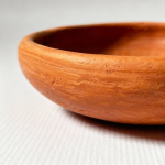 Close-up detail of natural terracotta earthen plate showing textured surface and smooth rim