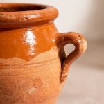 Close-up of tangia pot terracotta clay handle detail, showing artisan craftsmanship and honey-brown glaze