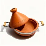 Terracotta tagine pot opened showing round clay base with metal rim and conical lid beside